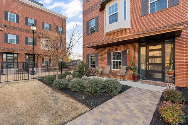 doorway to property featuring fence and brick siding