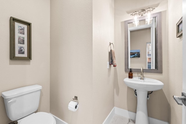 bathroom featuring toilet, marble finish floor, and baseboards