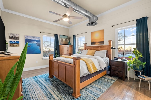 bedroom with baseboards, wood finished floors, visible vents, and crown molding