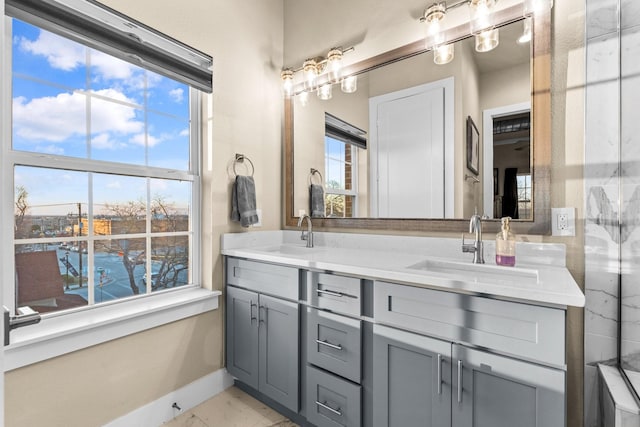 full bath with marble finish floor, a sink, baseboards, and double vanity