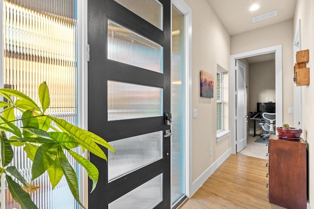 entryway with baseboards, visible vents, and wood finished floors