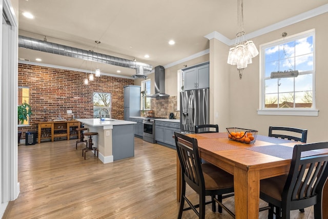 dining room with ornamental molding, light wood-style flooring, and brick wall