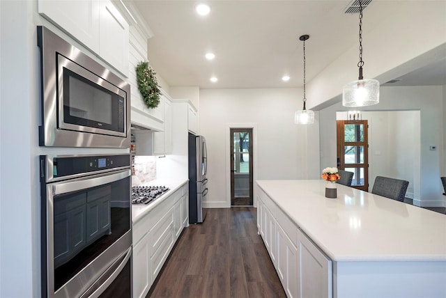 kitchen with stainless steel appliances, a center island, white cabinets, and light countertops