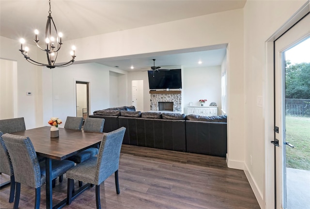 dining space with recessed lighting, ceiling fan with notable chandelier, dark wood-type flooring, a fireplace, and baseboards