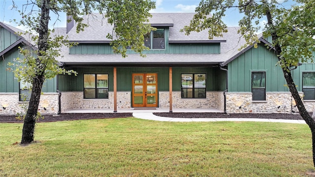 view of front of home featuring stone siding, a shingled roof, board and batten siding, and a front yard