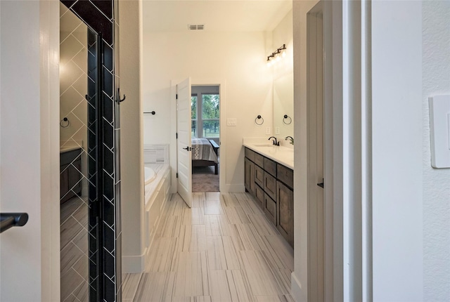 ensuite bathroom with visible vents, connected bathroom, vanity, and a garden tub