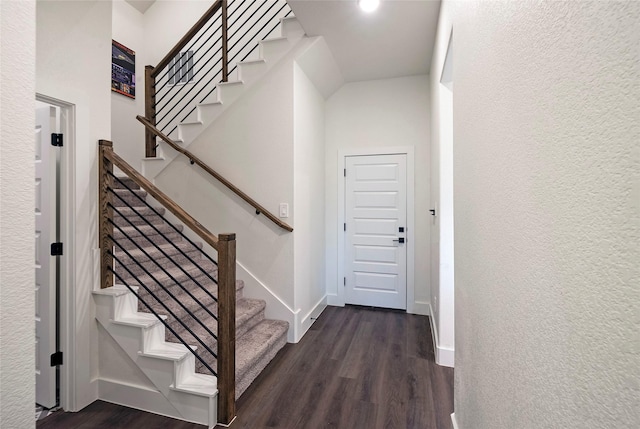 stairway featuring a textured wall, wood finished floors, and baseboards