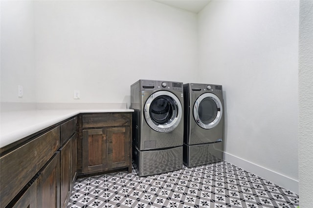 laundry room featuring cabinet space, washing machine and dryer, baseboards, and light floors