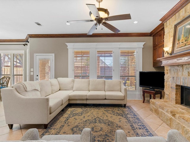 living room featuring a fireplace with raised hearth, plenty of natural light, visible vents, and crown molding