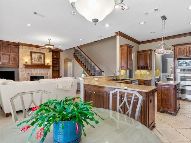 kitchen featuring light tile patterned floors, stainless steel appliances, visible vents, ornamental molding, and a sink