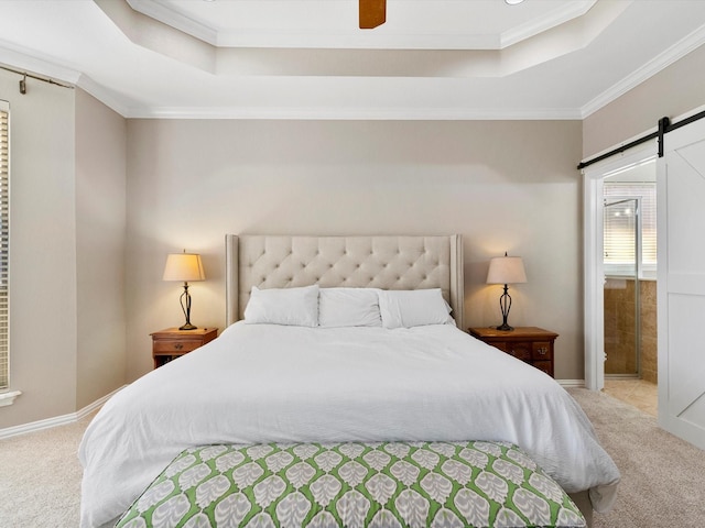 carpeted bedroom featuring a raised ceiling, crown molding, ensuite bathroom, and a barn door