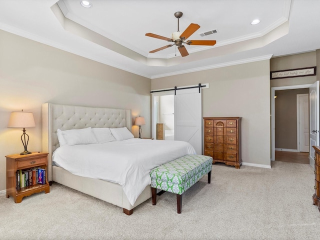 bedroom with a tray ceiling, visible vents, a barn door, ornamental molding, and light carpet