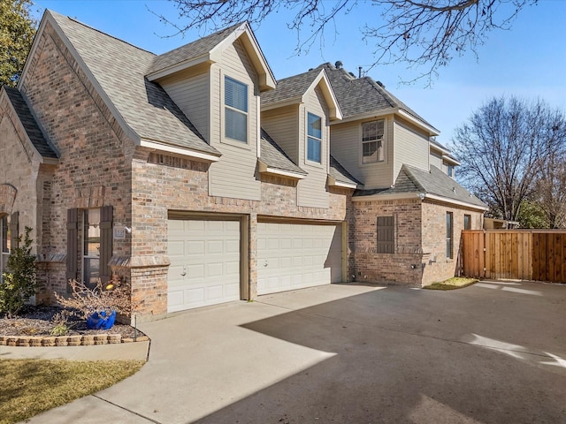 view of front facade featuring an attached garage, brick siding, fence, concrete driveway, and roof with shingles