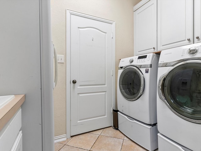 clothes washing area featuring cabinet space, washing machine and dryer, and light tile patterned floors