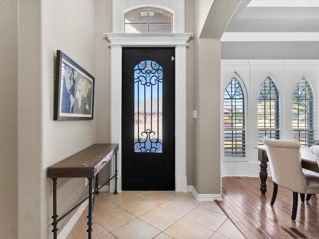 entrance foyer featuring light tile patterned floors, baseboards, and arched walkways