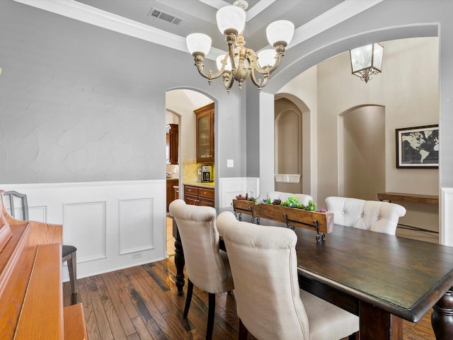 dining area featuring a notable chandelier, visible vents, a decorative wall, ornamental molding, and dark wood-type flooring