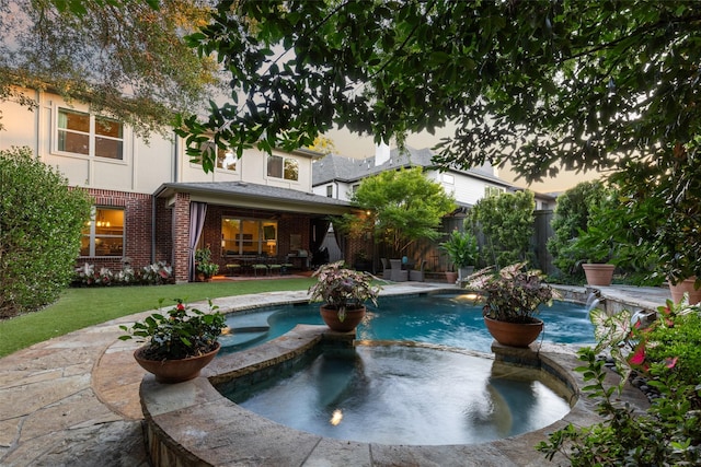 view of pool featuring a yard, a pool with connected hot tub, fence, and a patio