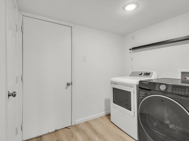 laundry room with laundry area, independent washer and dryer, light wood-style flooring, and baseboards