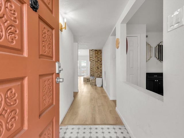 hallway featuring light floors and baseboards