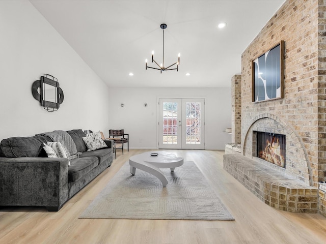 living room featuring light wood finished floors, recessed lighting, a brick fireplace, and french doors