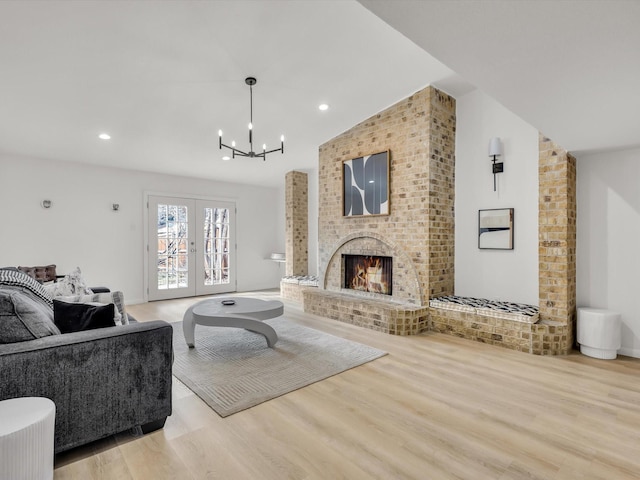 living room featuring wood finished floors, french doors, a fireplace, a notable chandelier, and recessed lighting