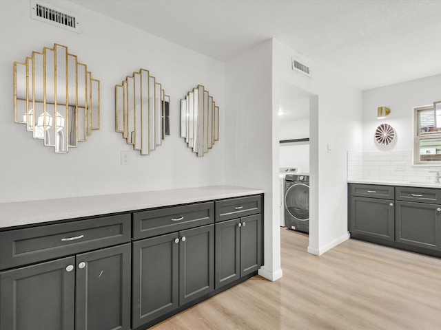 bathroom featuring washer / dryer, visible vents, decorative backsplash, and wood finished floors