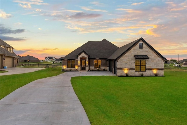 french country inspired facade featuring fence, concrete driveway, a front yard, a shingled roof, and a garage