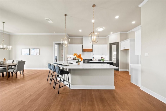 kitchen featuring a large island, light wood-style flooring, white cabinetry, and baseboards