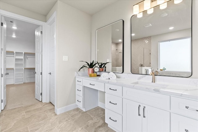 bathroom with a spacious closet, visible vents, baseboards, tiled shower, and vanity