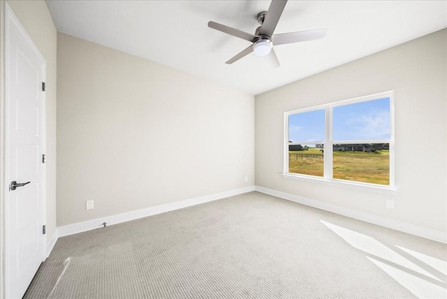 carpeted empty room with a ceiling fan and baseboards