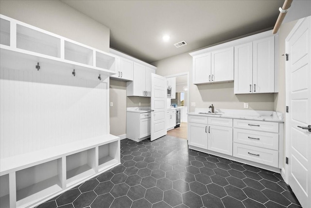 mudroom with visible vents, recessed lighting, dark tile patterned flooring, and a sink