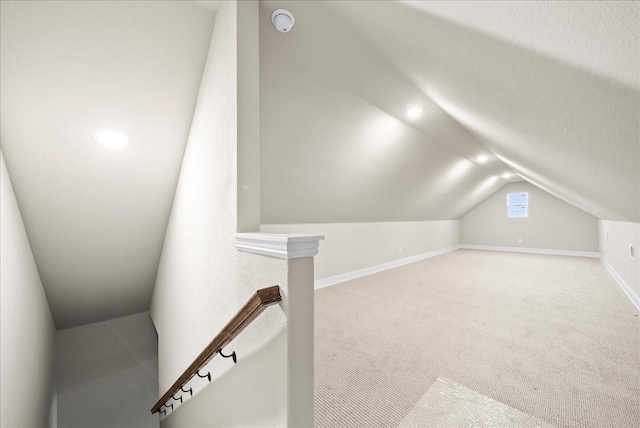 additional living space featuring carpet flooring, a textured ceiling, baseboards, and vaulted ceiling