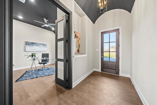 entrance foyer with baseboards, wood finished floors, and ceiling fan with notable chandelier