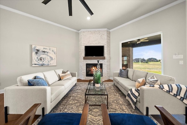 living room featuring ornamental molding, a fireplace, baseboards, and ceiling fan