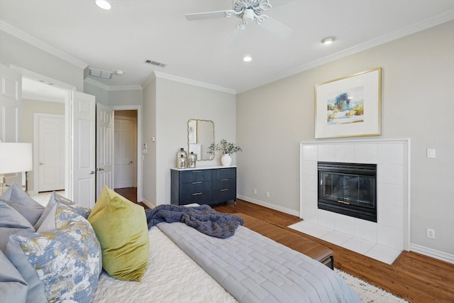 bedroom with dark wood-style floors, recessed lighting, ornamental molding, a tile fireplace, and baseboards