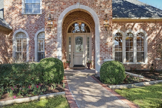 property entrance with a shingled roof and brick siding