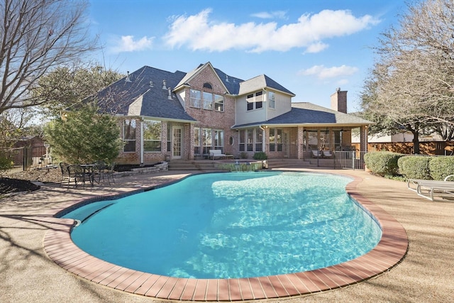 view of pool with a patio area, fence, and a pool with connected hot tub