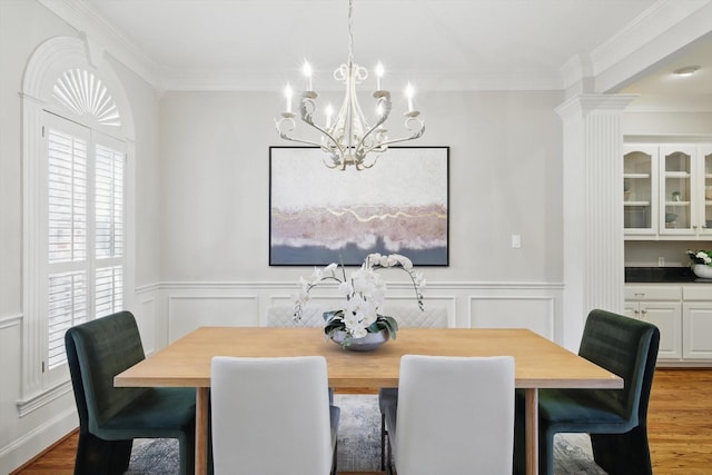 dining area with a wainscoted wall, crown molding, and wood finished floors