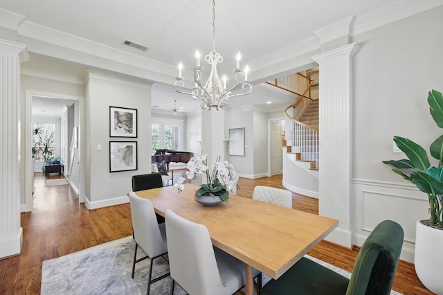 dining space featuring crown molding, visible vents, stairway, wood finished floors, and ornate columns