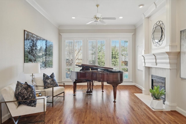 living area with a fireplace, crown molding, baseboards, and wood finished floors