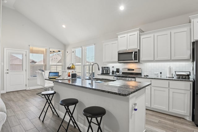 kitchen featuring tasteful backsplash, a breakfast bar, lofted ceiling, appliances with stainless steel finishes, and a sink