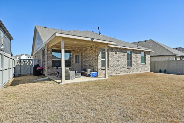 back of property with a patio, brick siding, a fenced backyard, and a lawn