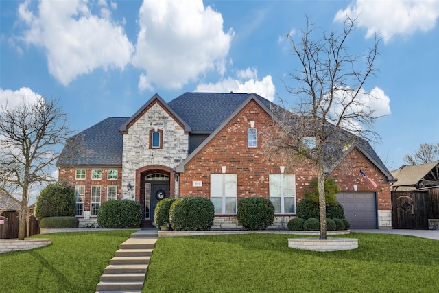 view of front of home with brick siding, roof with shingles, an attached garage, stone siding, and a front lawn