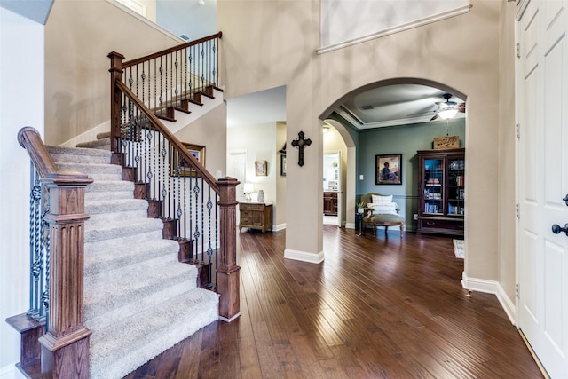 entrance foyer with a towering ceiling, hardwood / wood-style flooring, baseboards, and arched walkways