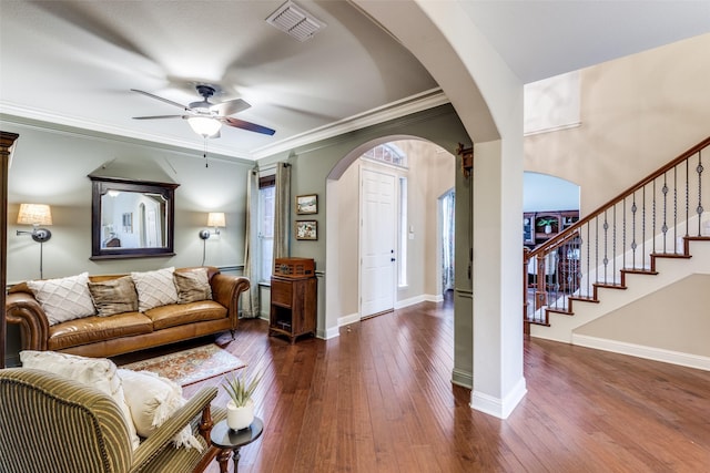 living area with ornamental molding, arched walkways, wood-type flooring, and stairway