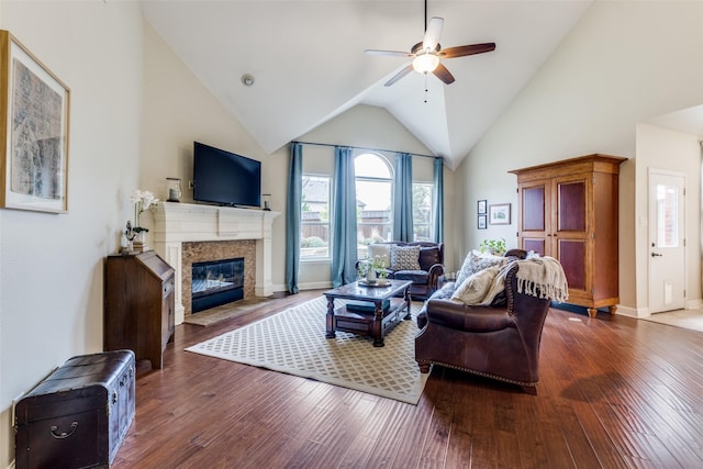 living area with high vaulted ceiling, wood-type flooring, a fireplace with flush hearth, and a ceiling fan