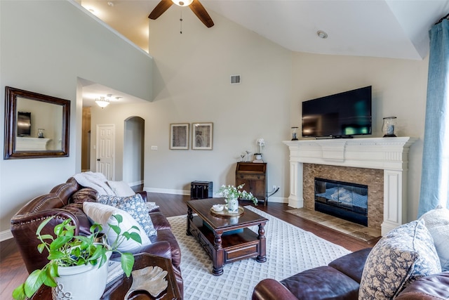 living room with arched walkways, a premium fireplace, ceiling fan, wood finished floors, and baseboards