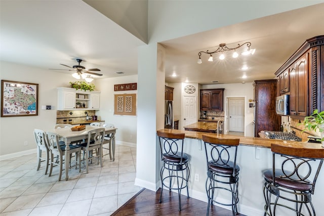 kitchen with stainless steel appliances, a breakfast bar area, a peninsula, and backsplash