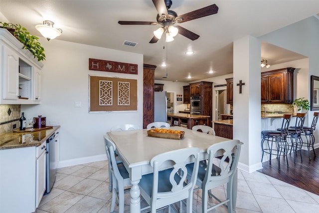 dining space with visible vents, ceiling fan, baseboards, and light tile patterned floors