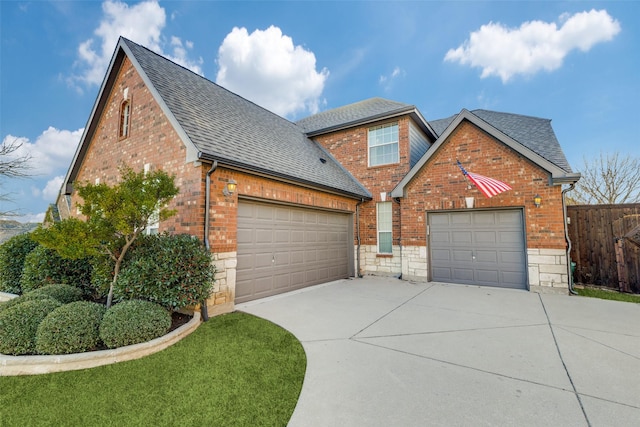 traditional-style home featuring concrete driveway, a shingled roof, an attached garage, and brick siding